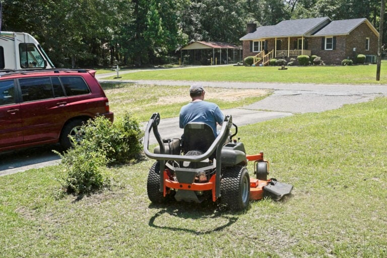 Professional landscaper cutting grass in a residential neighborhood with a zero turn lawnmower