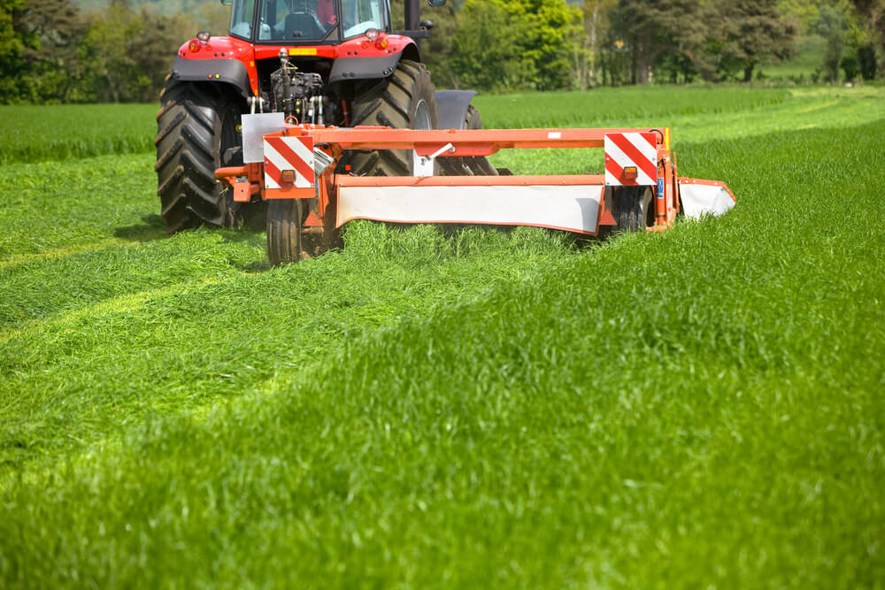 farm tractor with a large flail attachment for cutting grass and pasture