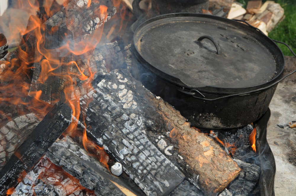 Cooking on the open fire using an iron pot.