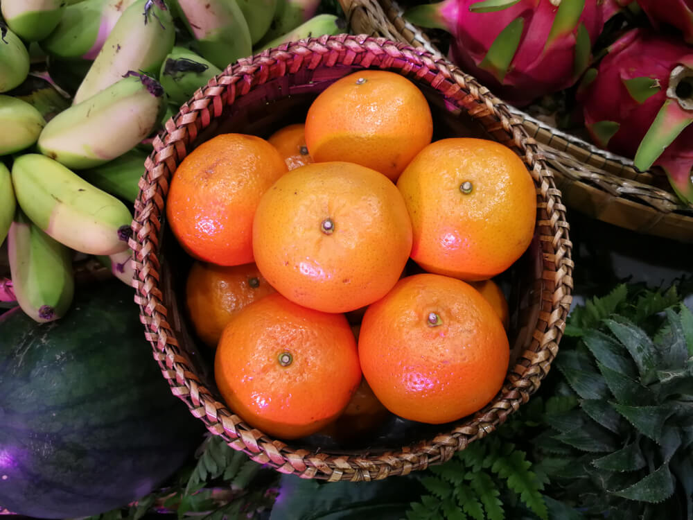 A reed woven basket stuffed with fresh orange fruits.