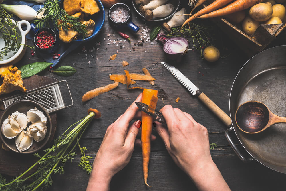Carefully peeling carrots alongside other yummy garden ingredients.