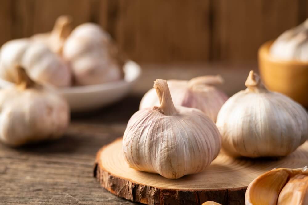 Fresh garlic cloves resting on a wooden cutting board.
