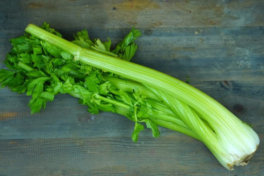Fresh green celery stalks atop a wooden table.