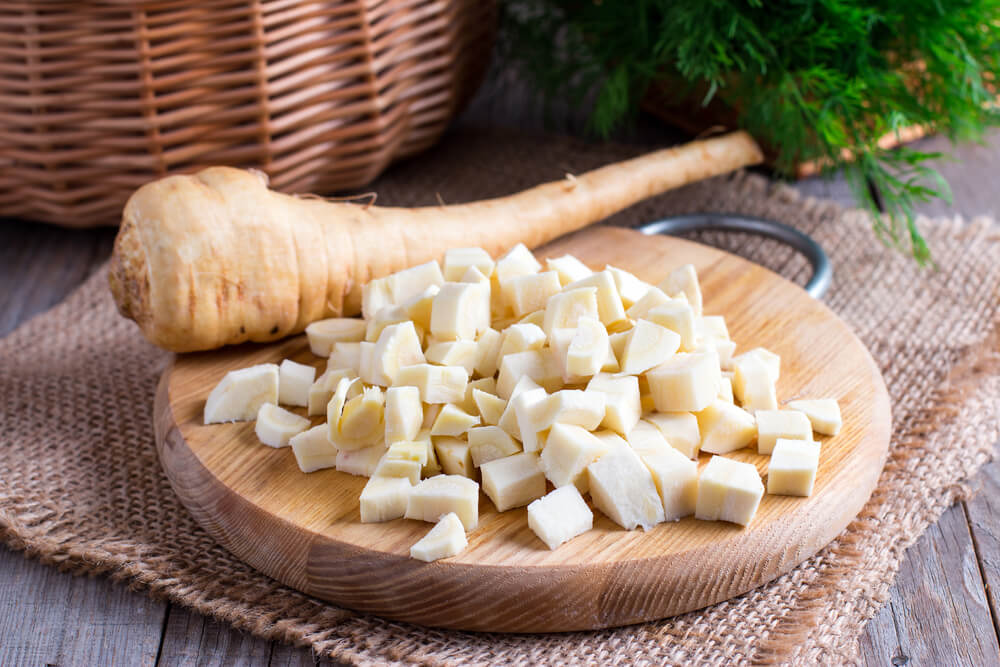 Freshly sliced parsnips resting on a wooden cutting board.