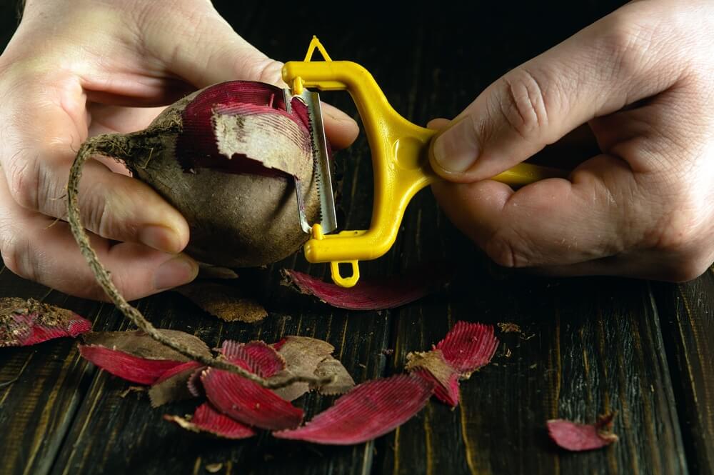 Using a veggie peeler to prepare yummy beets.