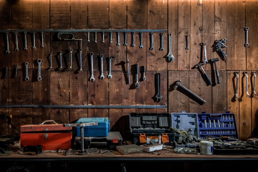 A garage workshop with neatly organized tools hanging on the wall with various toolboxes.