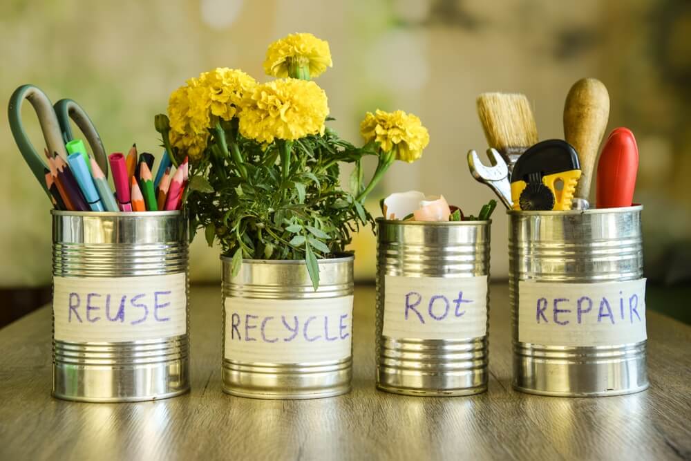 Repurposing old cans by holding flowers tools and writing utensils.