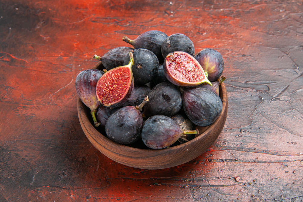 Delicious black mission figs harvested in a small brown pot.