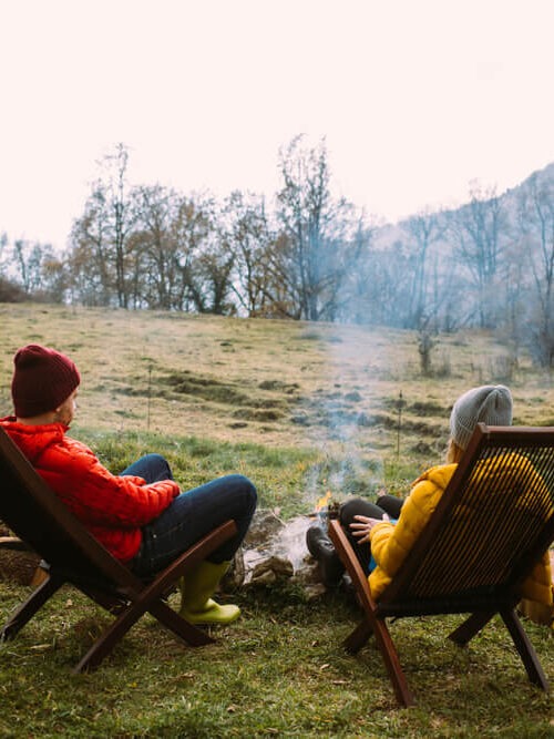 couple in warm puffy jackets enjoying a cozy campfire