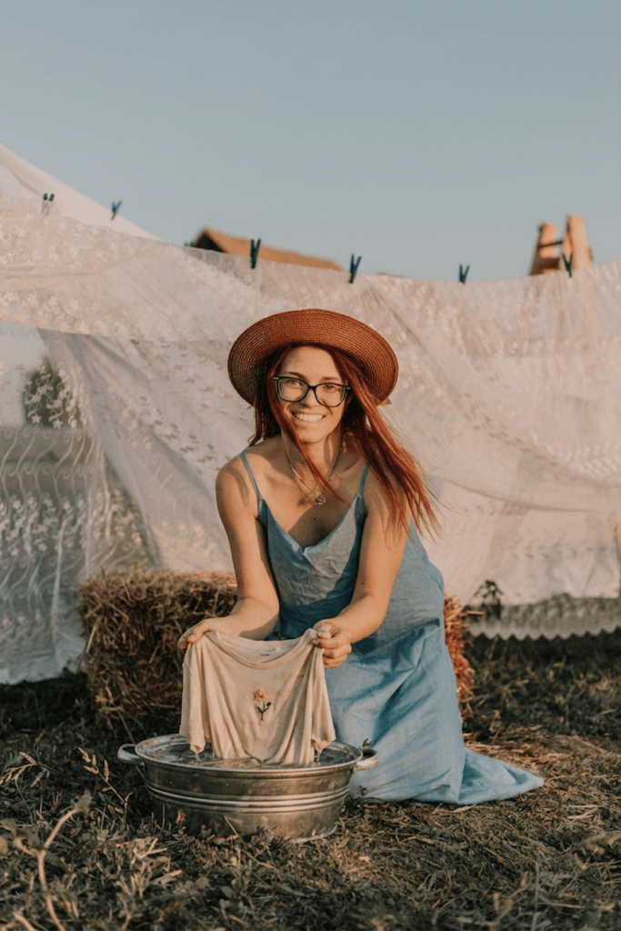 Lady washing clothes off the grid in a metal bucket with washing hanging on the clothesline